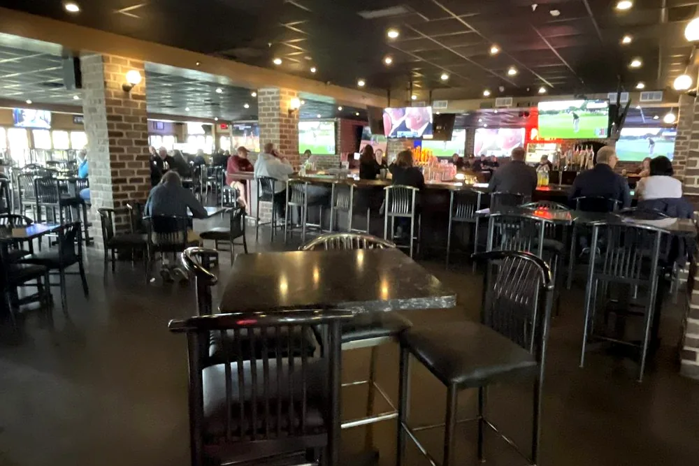 The main bar at the 18th Amendment, with high tables, stools and a row of TVs showing the game
